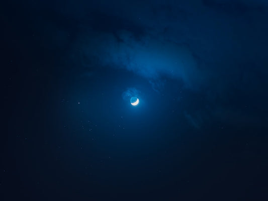 A crescent moon in a dark, cloudy night sky, illustrating the serene habitat ideal for powder blue isopods as discussed in the care article.