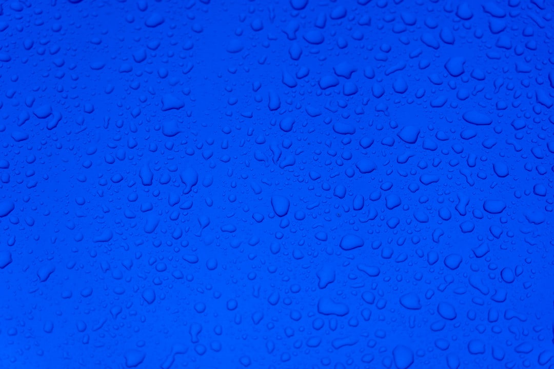 Close-up of water droplets on a vibrant blue surface, illustrating the humid environment ideal for powder blue isopods.