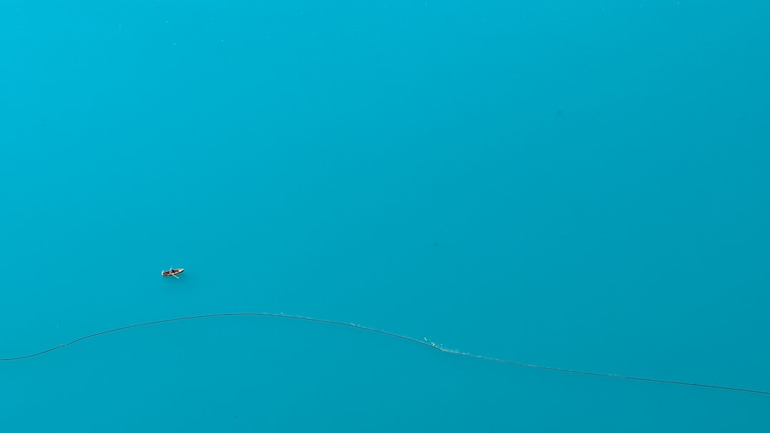 A small boat floats on a vast, calm blue lake, symbolizing tranquility similar to the serene habitat ideal for powder blue isopods.